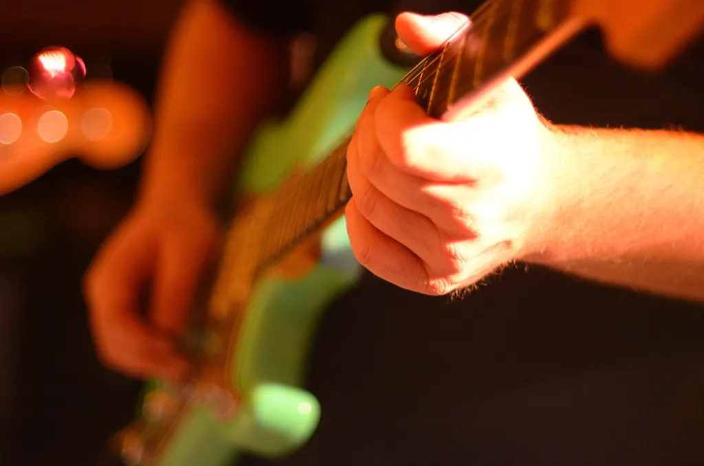 A student playing guitar under warm studio light
